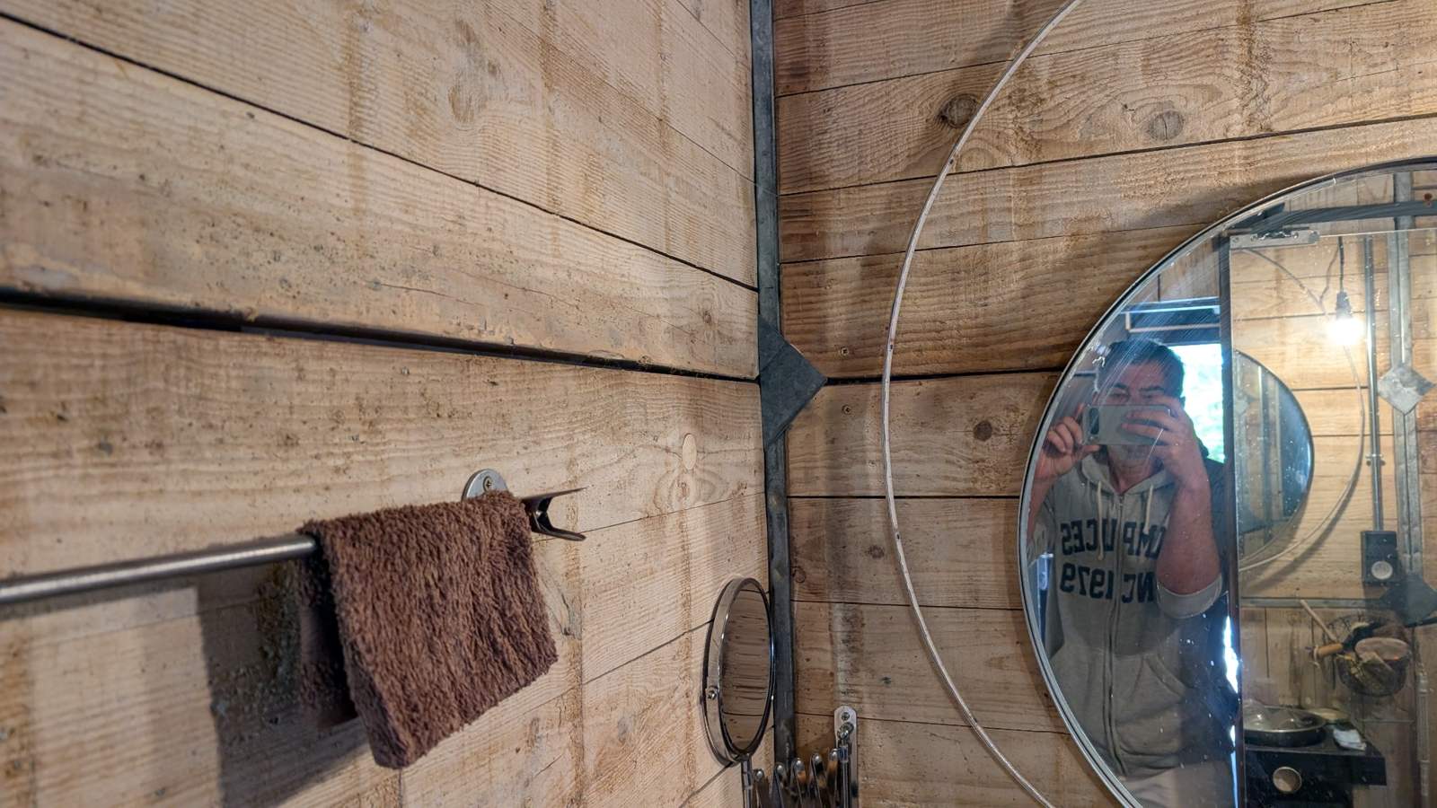 Miroir rond sur panneaux de coffrage en bois et métal